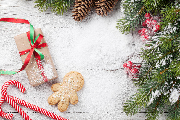 クリスマス プレゼント ボックス、キャンデー杖、木製のテーブルにジンジャーブレッド男と雪モミの木。あなたの挨拶のためのスペースのトップ ビュー - 写真・画像