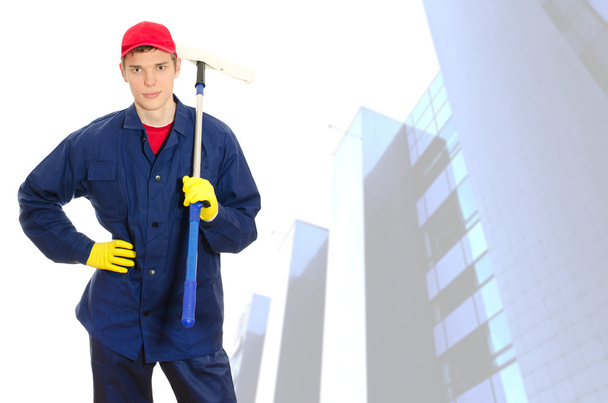 Young male window cleaner with wiper over building with glass facade - Photo, Image