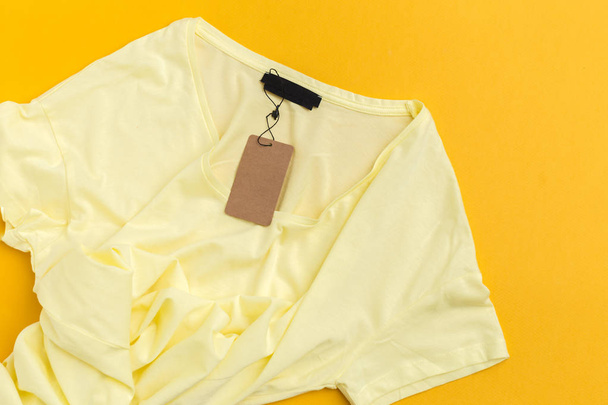 Yellow t-shirt with blank label tag top view - Foto, Imagen