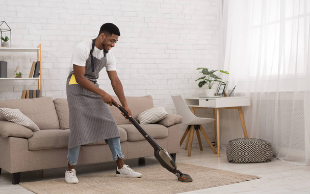 Homem preto casa de limpeza com aspirador sem fio
 - Foto, Imagem