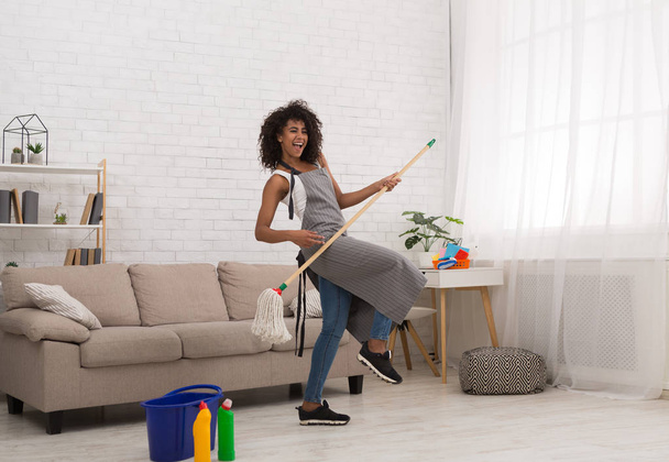 Black woman playing air guitar with mop - Photo, Image