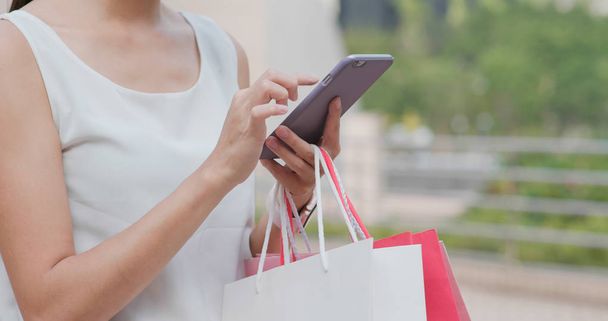 Kadın alışveriş torbaları ve istimal hareket eden telefon ile tutun - Fotoğraf, Görsel