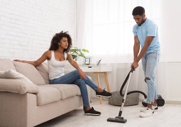 Kobieta relaks podczas czarny człowiek sprzątanie mieszkania - Zdjęcie, obraz