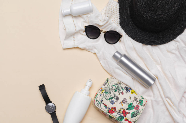 Composition of white dress, black straw hat, sunglasses, handbag and other accessories on pastel background top view - Foto, Imagen