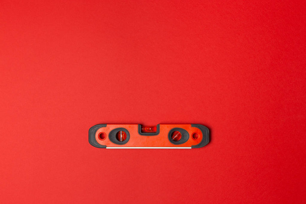 Red mini construction level on red background, top view - 写真・画像