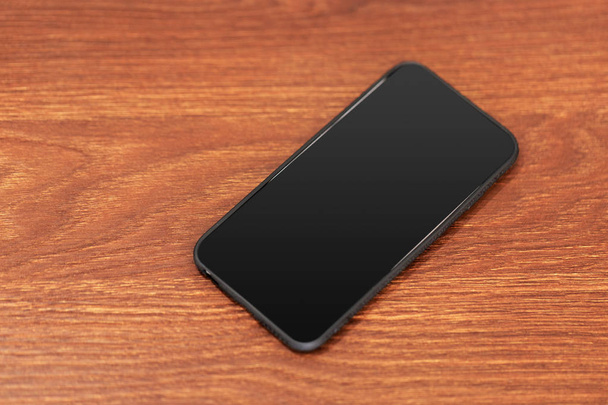 Mobile phone with blank screen on wooden table background. - Foto, Bild