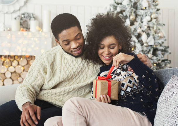 Mutlu kız erkek arkadaşıyla Noel hediyesi unwrapping - Fotoğraf, Görsel