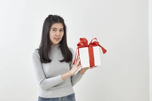 Joven mujer asiática muestran OK con una caja de regalo sobre fondo de pared gris brillante
 - Foto, Imagen
