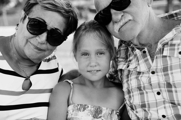 Бабушка с дедушкой и внучка наслаждаются днем в парке
 - Фото, изображение