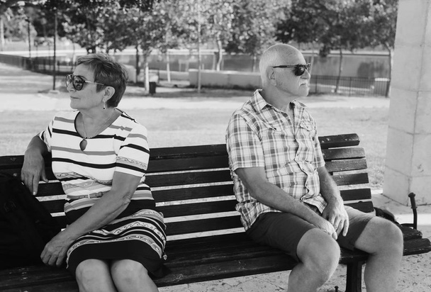 Elderly couple are sitting upset on a bench in a park . Family quarrel. - Photo, Image