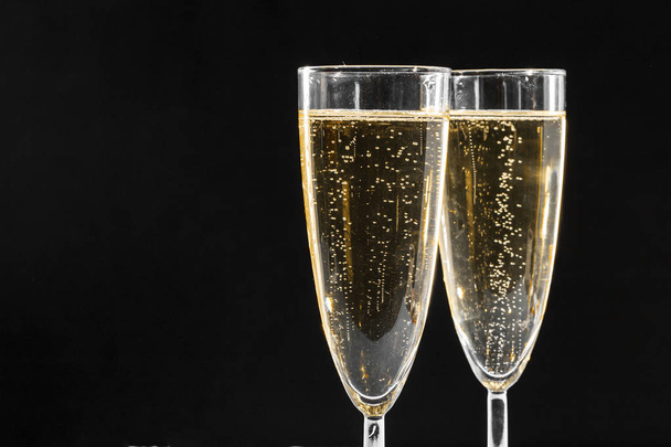 close up of two glasses of sparkling wine against blakc background  - Foto, Imagem