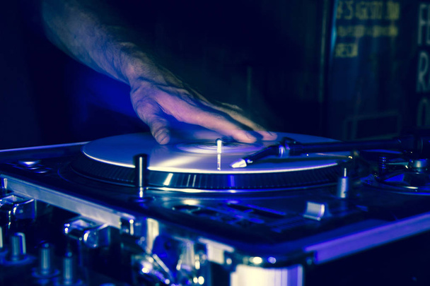 As mãos de um DJ durante a reprodução de discos de vinil durante uma festa, as mãos estão se movendo e são duplas para um efeito estroboscópico do flash durante a filmagem
 - Foto, Imagem