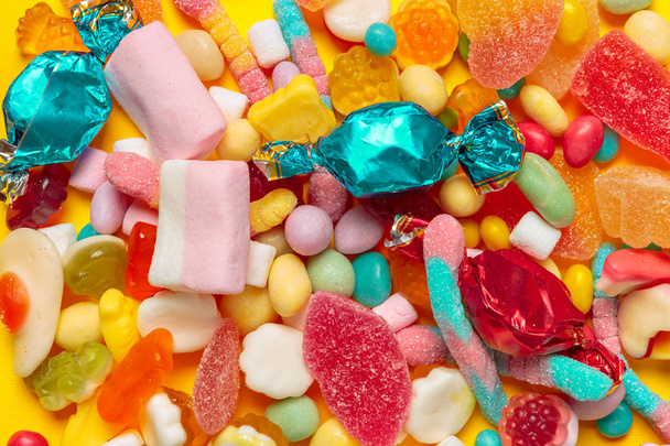 top view of colored candies on yellow background - Foto, afbeelding