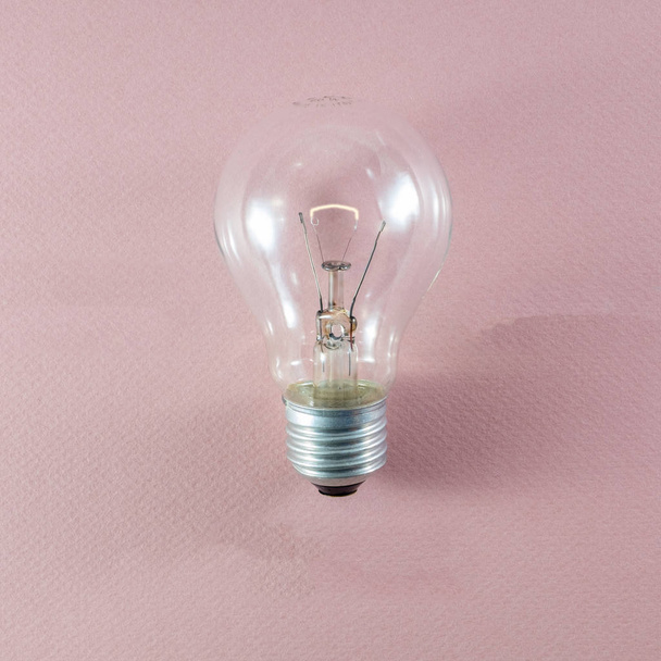Glass incandescent tungsten filament light bulb being replaced due to energy consumption considerations - Photo, Image