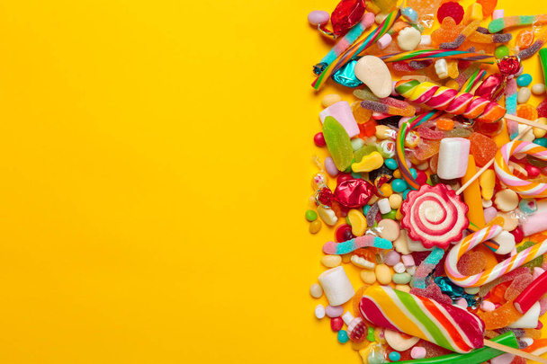 top view of colored candies on yellow background - Foto, Imagem
