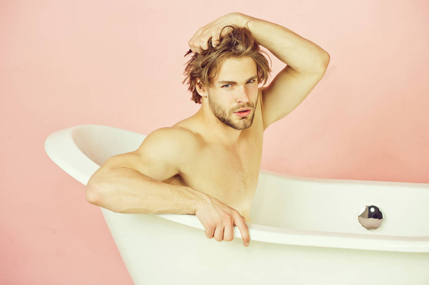 hombre con cuerpo musculoso sentado en bañera blanca
 - Foto, imagen