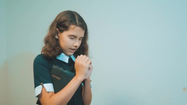 kleine meisje Heilige Bijbel bidt met Bijbel in haar handen. de Heilige Bijbel katholicisme. kinderen en religie opvoeding geloof symbool. Meisje met bidden. Vrede levensstijl, hoop, dromen concept - Video