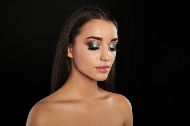 Portrait of young woman with eyelash extensions and beautiful makeup on black background - Φωτογραφία, εικόνα