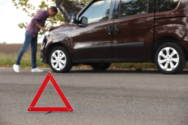 Emergency stop sign and driver near broken car on road. Auto insurance - Valokuva, kuva
