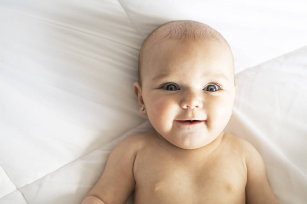 A Cute baby girl on a white bed at home - Fotografie, Obrázek