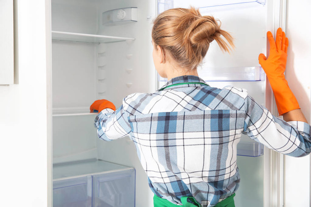 Nainen kumihanskat puhdistus tyhjä jääkaappi kotona
 - Valokuva, kuva