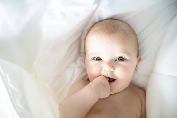 A Cute baby girl on a white bed at home - Фото, изображение