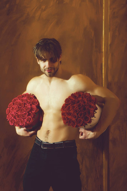 bearded muscular man with sexy body holds red rose box - Photo, image