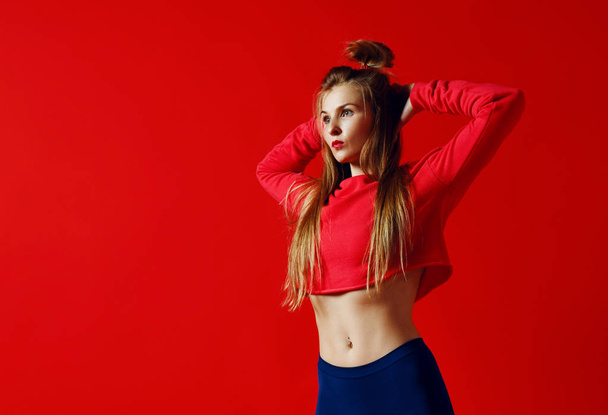 Cute sporty girl holding hands behind head, fitness, red background - Фото, зображення