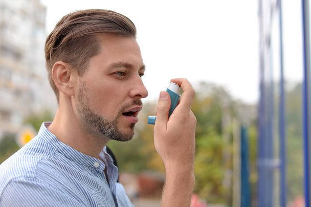 Man using asthma inhaler outdoors. Health care - Фото, зображення