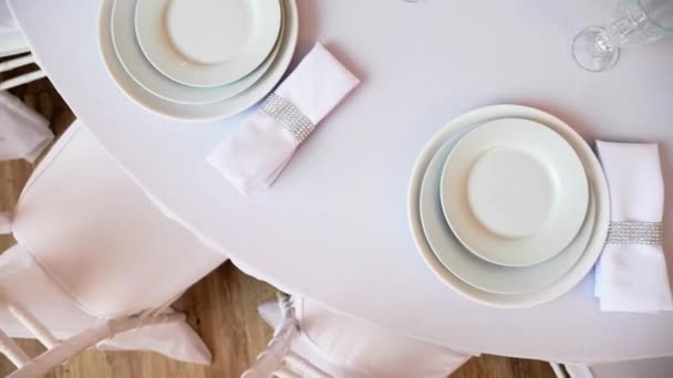 στρογγυλό τραπέζι με ένα λευκό τραπεζομάντιλο σερβίρεται κρασί πιάτων ποτηριών και χαρτοπετσέτες - Πλάνα, βίντεο
