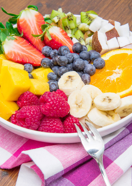 salada de frutas com bagas frescas, laranja, coco, manga e fatias de banana
  - Foto, Imagem