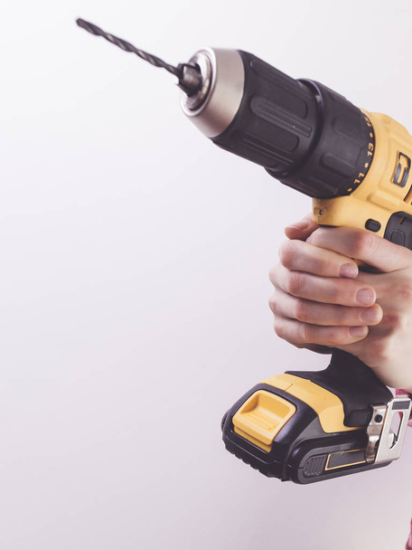 Unrecognizable woman holding yellow driller about to drill something. Hardware construction site objects concept. - Photo, Image