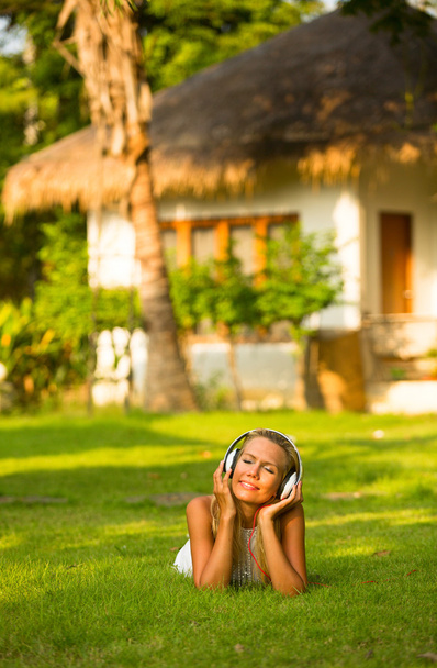 Menina emocional bonita com fones de ouvido desfrutando da natureza e da música no dia ensolarado
. - Foto, Imagem
