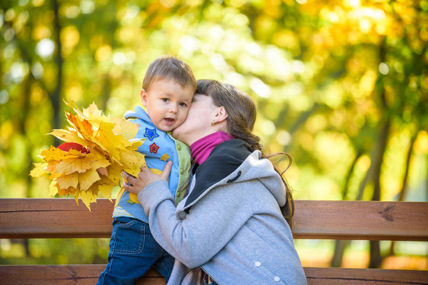 Rodzinne zabawy na świeżym powietrzu. Mama i syn razem. Matka i dziecko chłopiec przytulanie w jesienny park. - Zdjęcie, obraz
