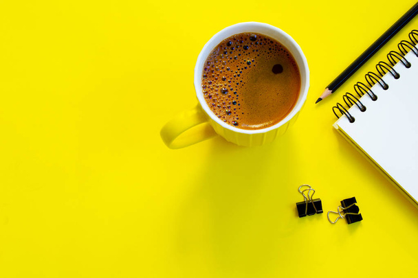 Σημειωματάριο, μολύβι και Καφές Κύπελλο σε κίτρινο φόντο. - Φωτογραφία, εικόνα