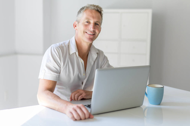 Mature Man Using Laptop On Desk At Home - Zdjęcie, obraz