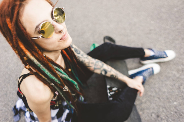 young girl with tattoo and dreadlocks sitting in the park - Photo, Image