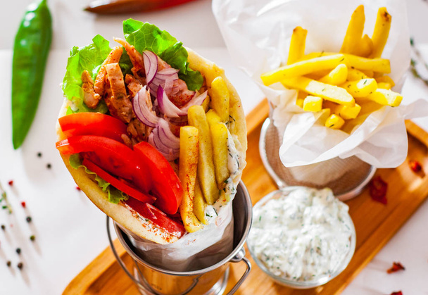 giroscópios de carne de cordeiro grego com molho tzatziki, legumes, queijo feta e batatas fritas
 - Foto, Imagem