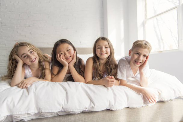 large group of her friends taking goog time on bed - Photo, image
