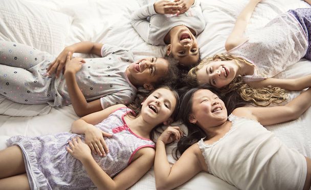 large group of her friends taking goog time on bed - Фото, изображение