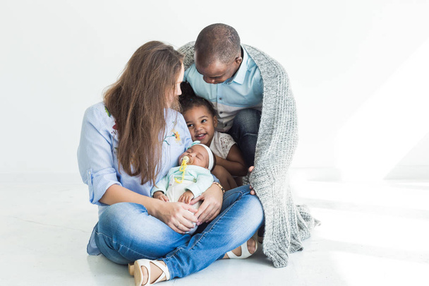 Loving father covers his family with a plaid. Happy multiethnic family. Family values - Фото, зображення