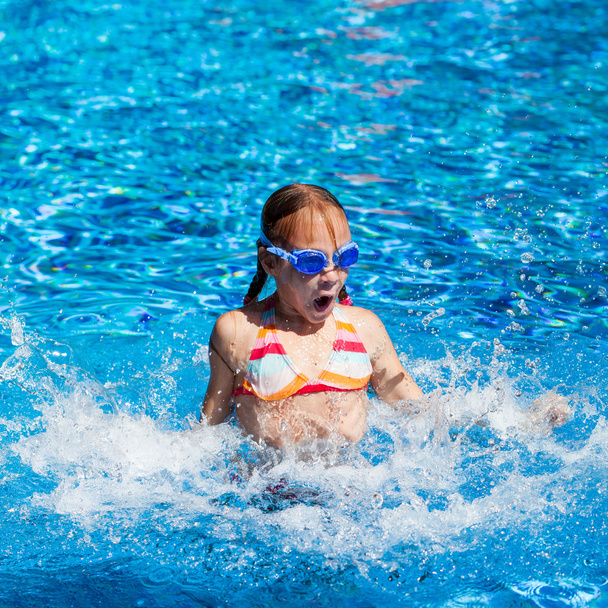 happy little girl splashing around in the pool - Zdjęcie, obraz