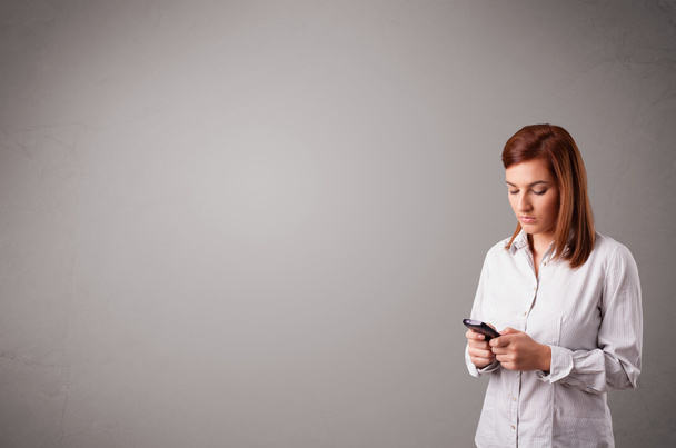 young lady standing and holding a phone with copy space - Photo, image