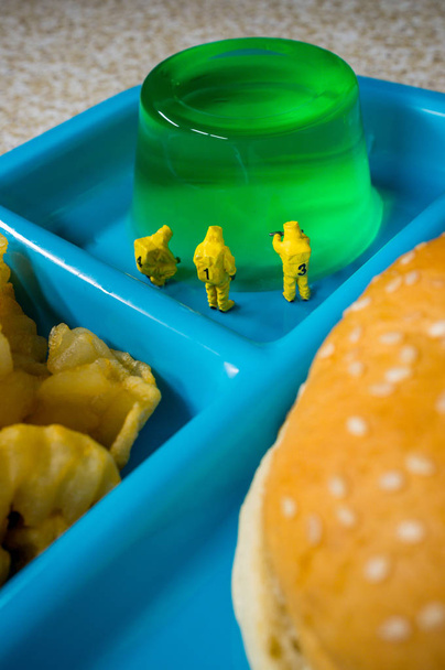 Equipo de materiales peligrosos en miniatura que inspecciona el valor nutricional del almuerzo escolar de comida rápida poco saludable - Foto, imagen
