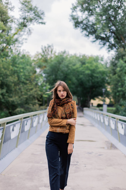 A very beautiful girl is standing on an iron bridge and is posing on the camera. - Foto, afbeelding