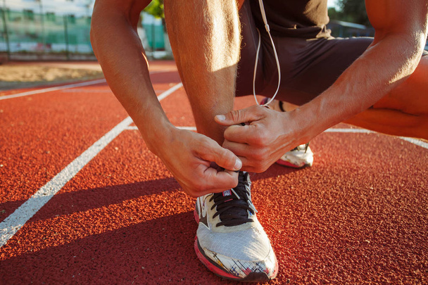 Nuori mies juoksija sitominen kengännauhat
  - Valokuva, kuva