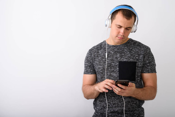 Студийный кадр молодого мускулистого человека, слушающего музыку во время использования
 - Фото, изображение
