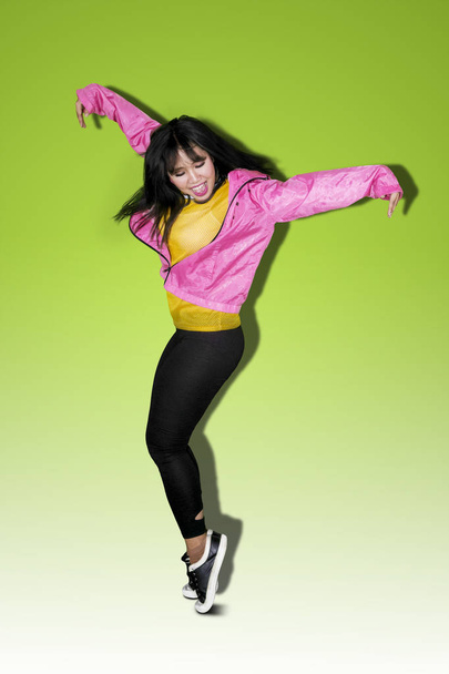 Beautiful woman looks happy while doing break dance in green screen - Foto, imagen