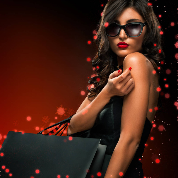Beautiful young woman make shopping in black friday holiday. Girl with black bag on dark background. - Foto, Imagen