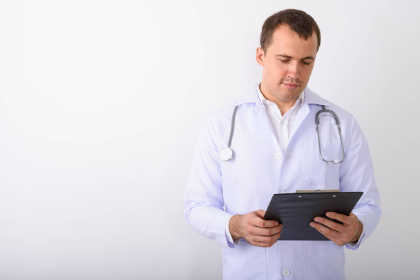 Studio shot of young muscular man doctor reading on clipboard ag - Photo, Image